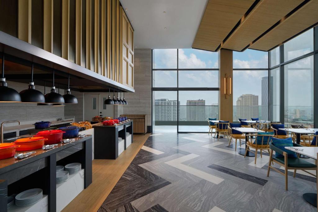 A bright breakfast room with a buffet counter and floor-to-ceiling city views.