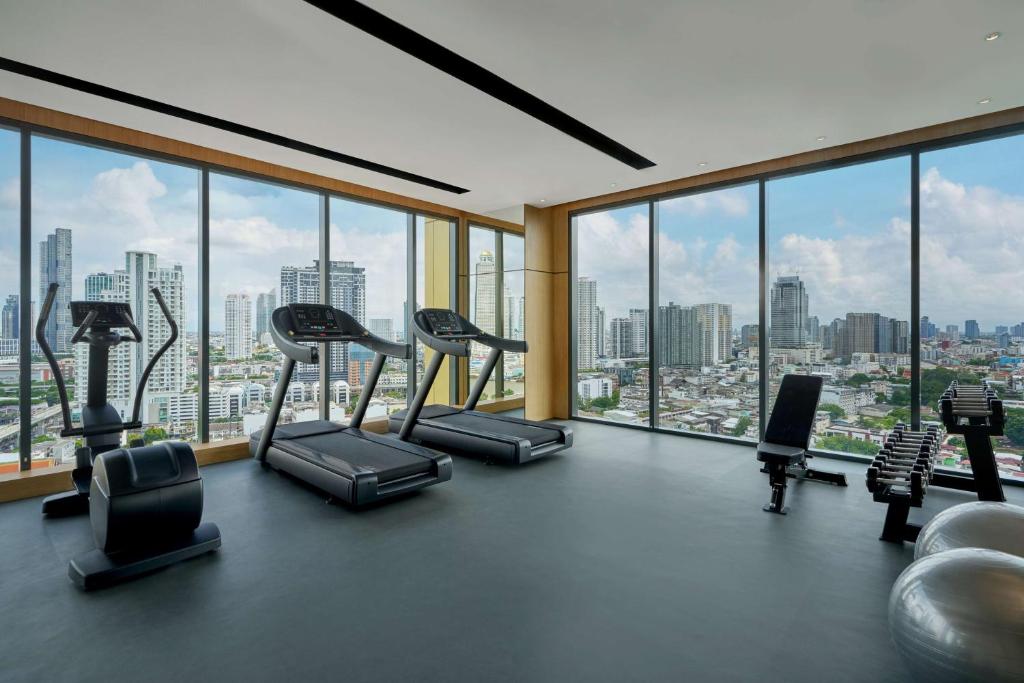A high-floor fitness room with cardio machines, free weights and expansive skyline views.