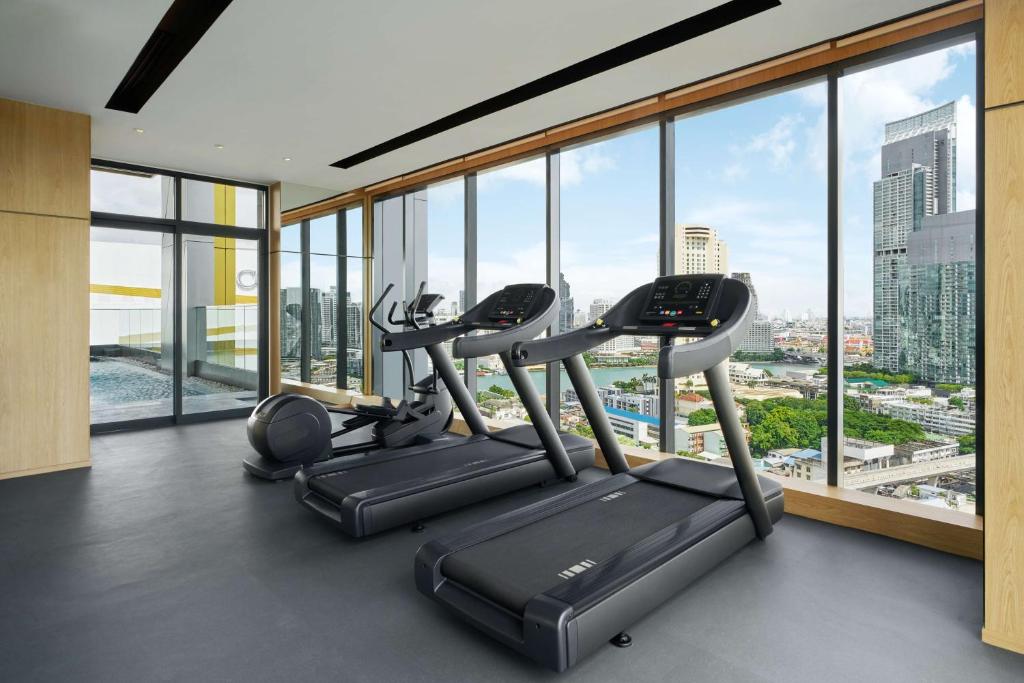 A compact cardio-focused gym with three treadmills facing a high-rise view.