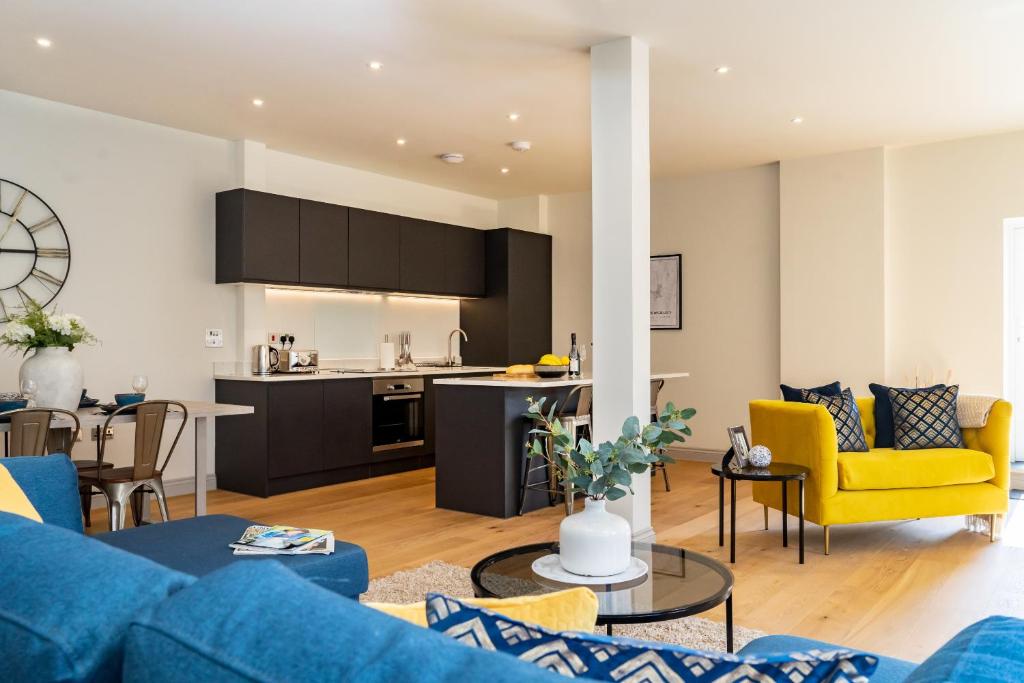 a living room with a blue couch and a kitchen at The Old Glassworks by Bevolve in Shrewsbury