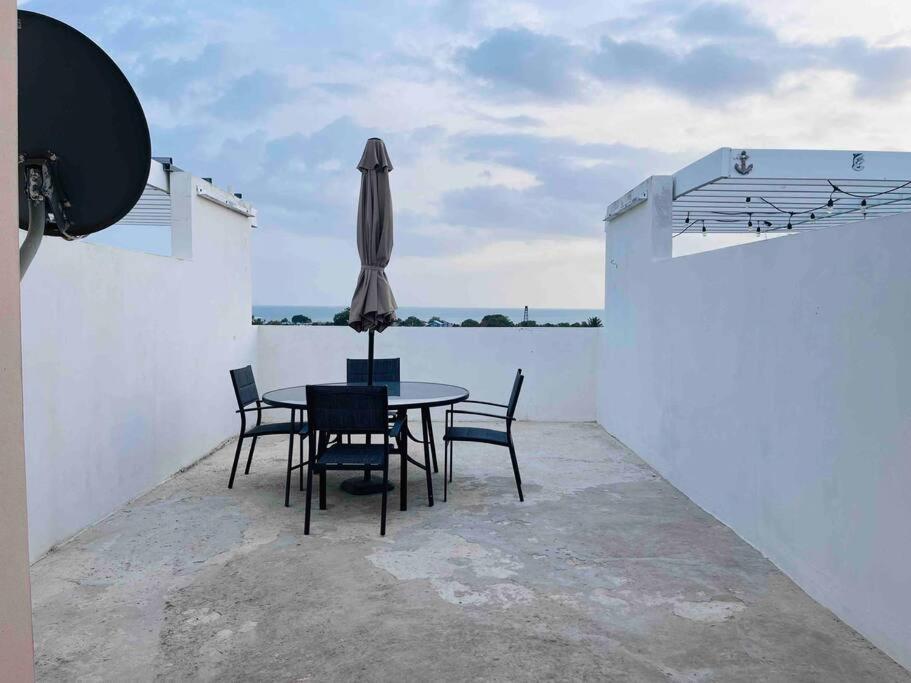 a patio with a table and chairs and an umbrella at Ubicación genial a 3 minutos de combate Beach in El Combate