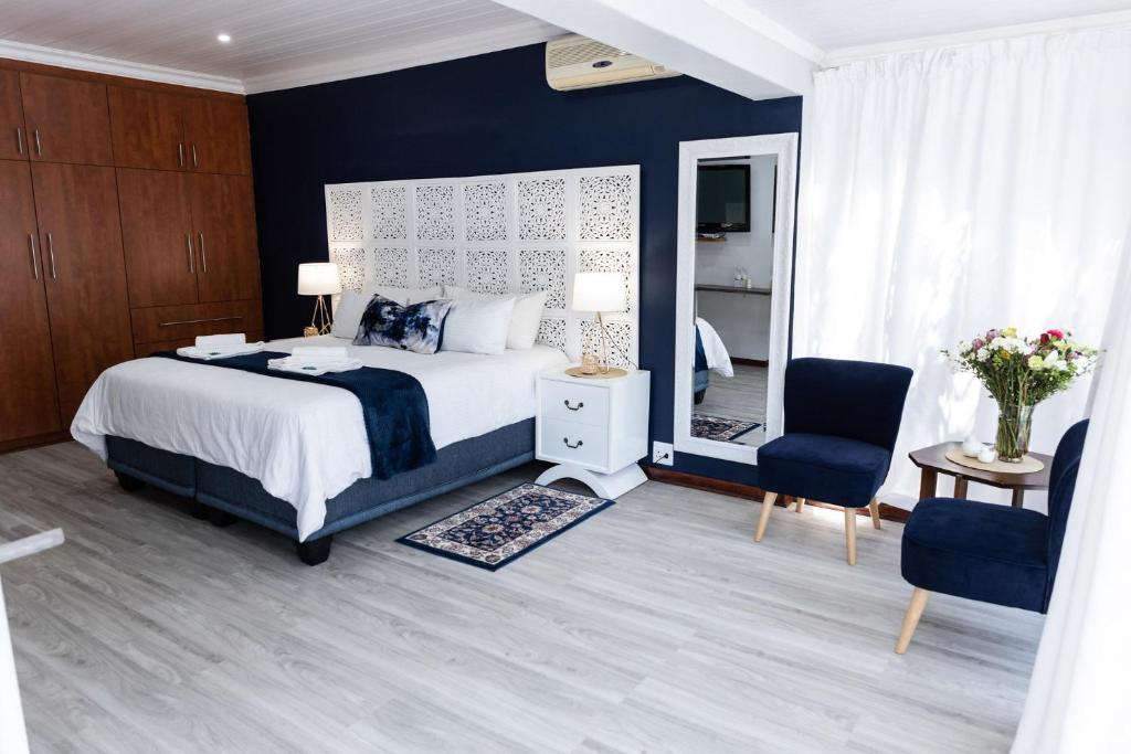 a bedroom with a bed and two chairs and a mirror at Gemstone Guest House in Klerksdorp