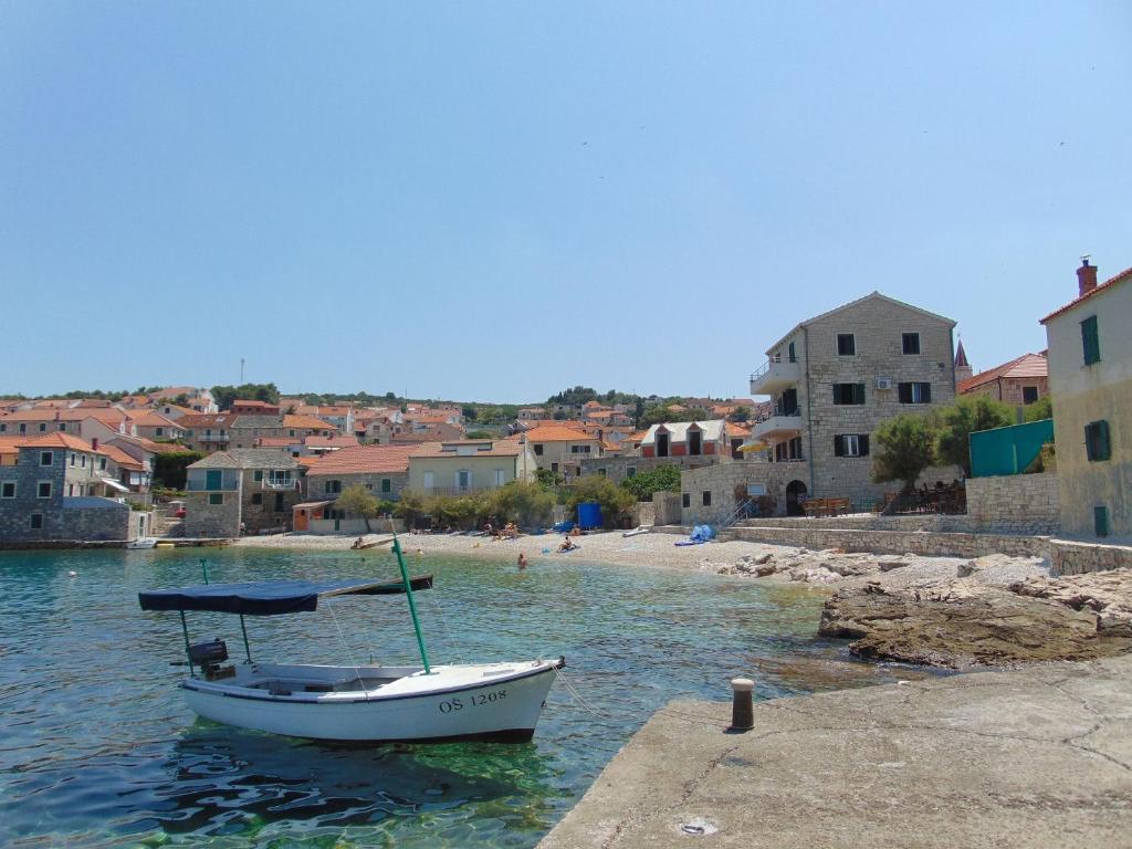 a boat sitting in the water next to a beach at Apartment Fran in Postira