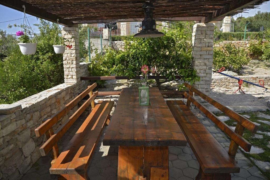 drewniany stół i ławki pod kamienną ścianą w obiekcie Apartments Toni w mieście Maslinica
