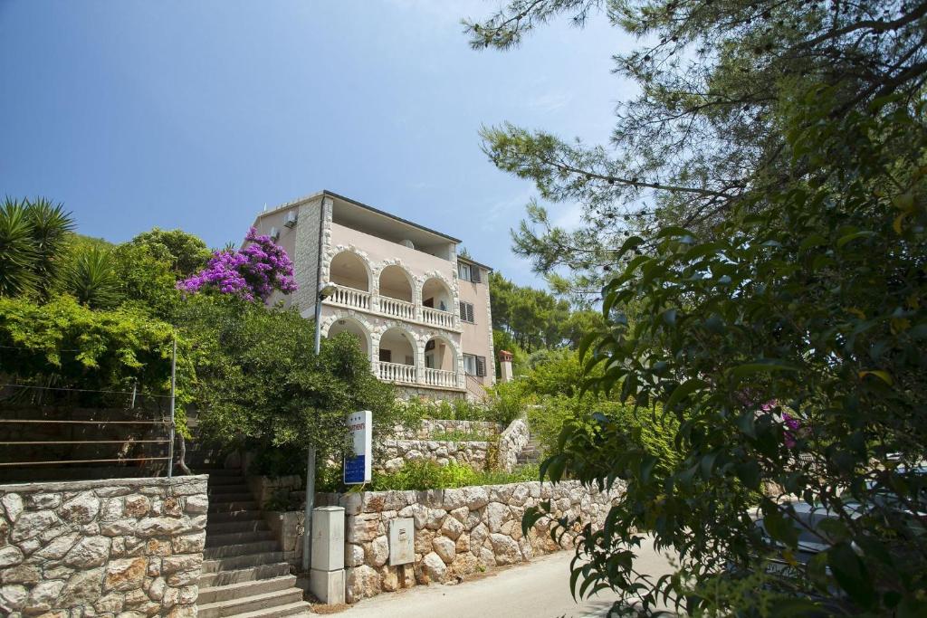 a house on a stone wall with purple flowers at Apartments Ante in Smokvica