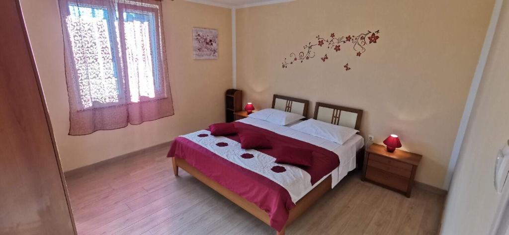 sypialnia z łóżkiem z czerwoną pościelą i białymi poduszkami w obiekcie Apartment Nadica w Fažanie