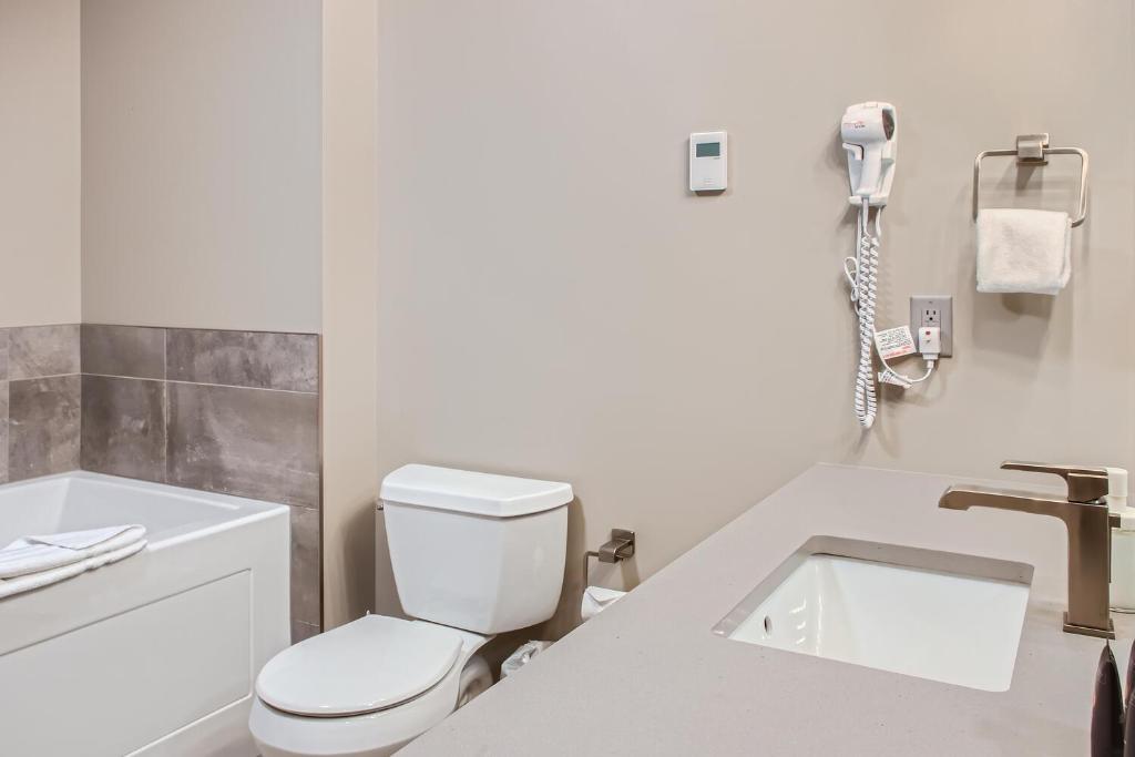 a white bathroom with a toilet and a sink at Stonegate Resort Unit B105 in Big White