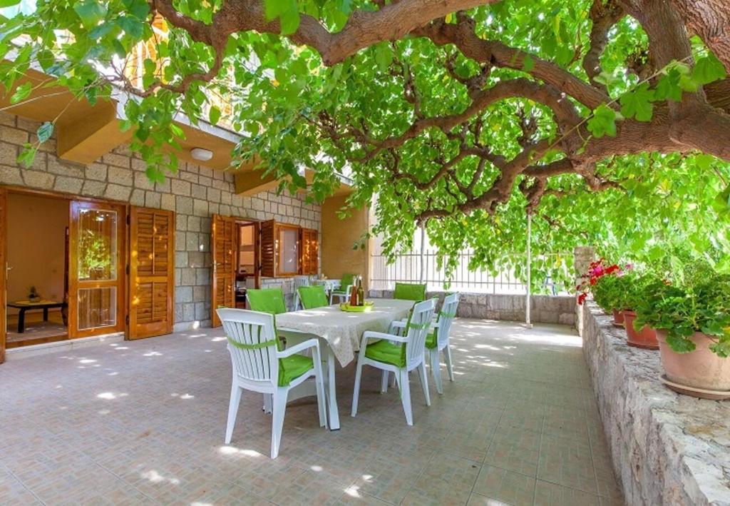 a table and chairs on a patio under a tree at House Zeljka in Podstrana