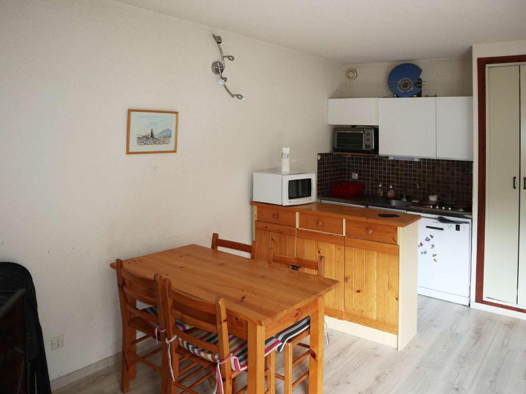 une cuisine avec une table en bois et un micro-ondes dans l'établissement Appartement Confort 6 Pers. Face Télésiège, Commerces & Animations - Les Orres 1650 - FR-1-322-592, aux Orres
