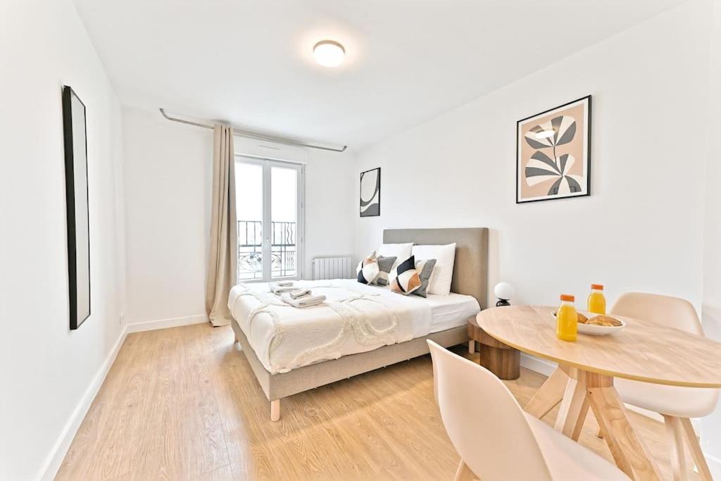 une chambre blanche avec un lit et une table dans l'établissement Studio charmant tout équipé Paris Montreuil - III, à Montreuil