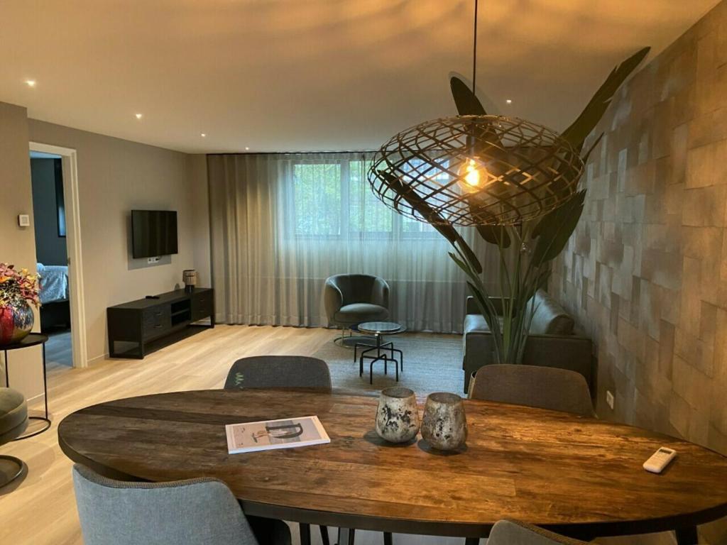 a living room with a wooden table and a room with a dining room at Welcome in - Luxe appartement in de hoofdstraat, met balkon en airco - Domburg in Domburg