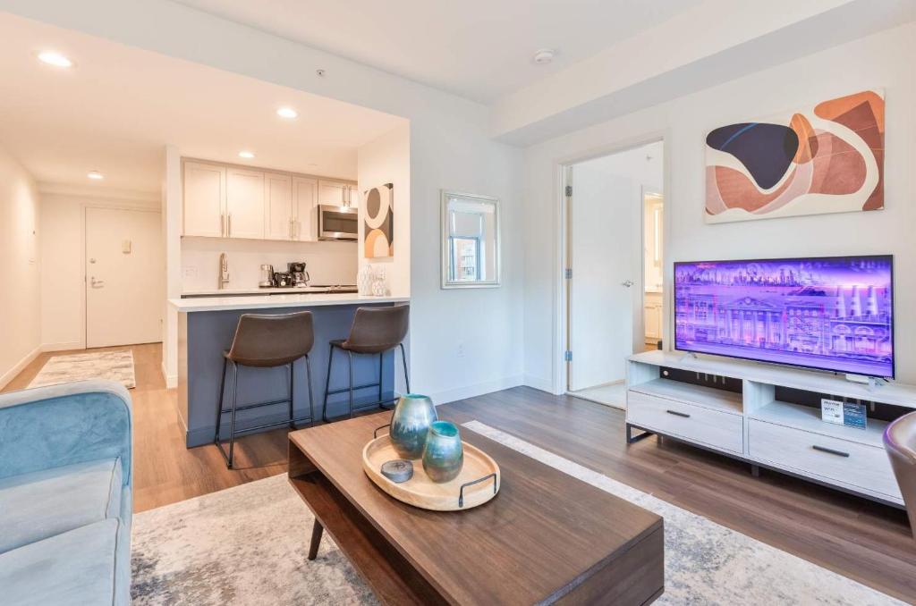 a living room with a table and a tv at Luxury Apt Near Kendall Square in Cambridge