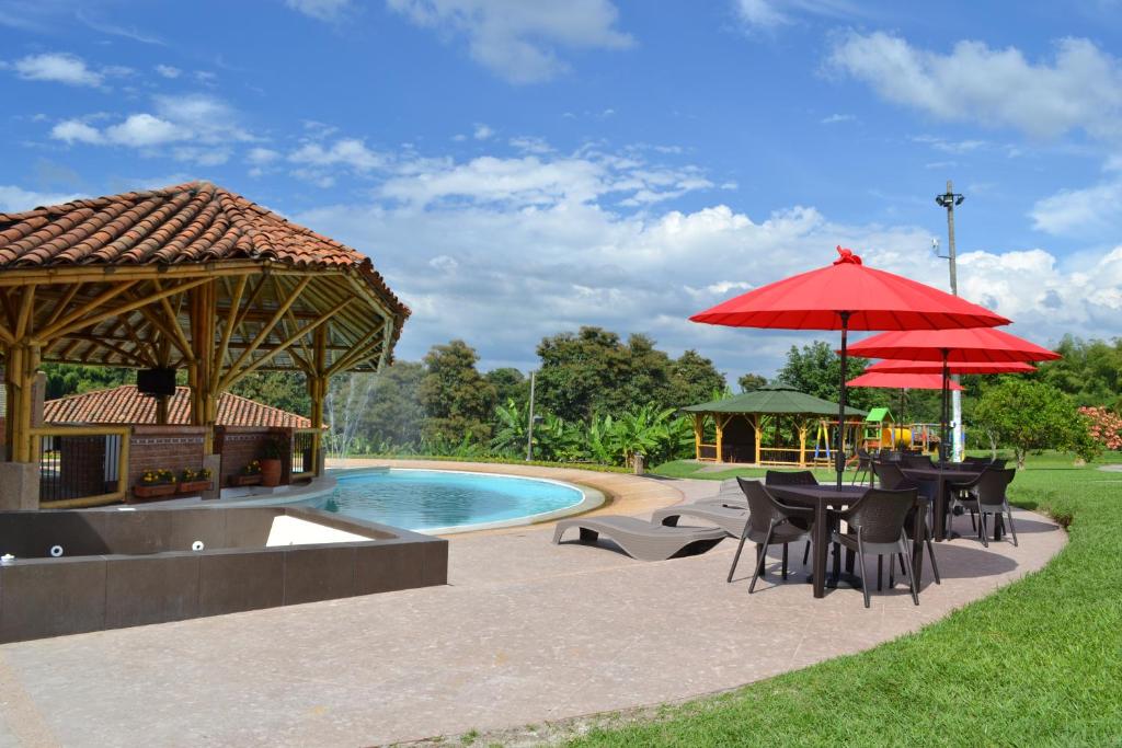 un patio con mesas y sombrillas junto a una piscina en Hotel Campestre Montecarlo, en Montenegro