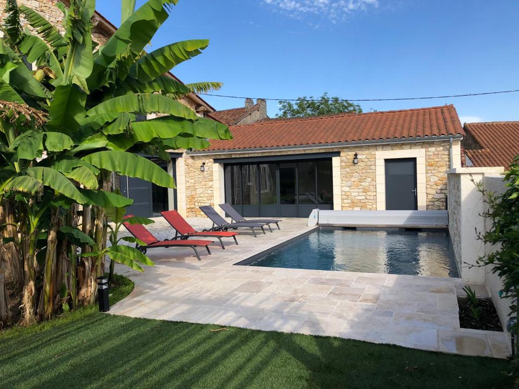 a backyard with a swimming pool and two lounge chairs at Gîte Chez Marcel & Marthe in Saint-Front-la-Rivière