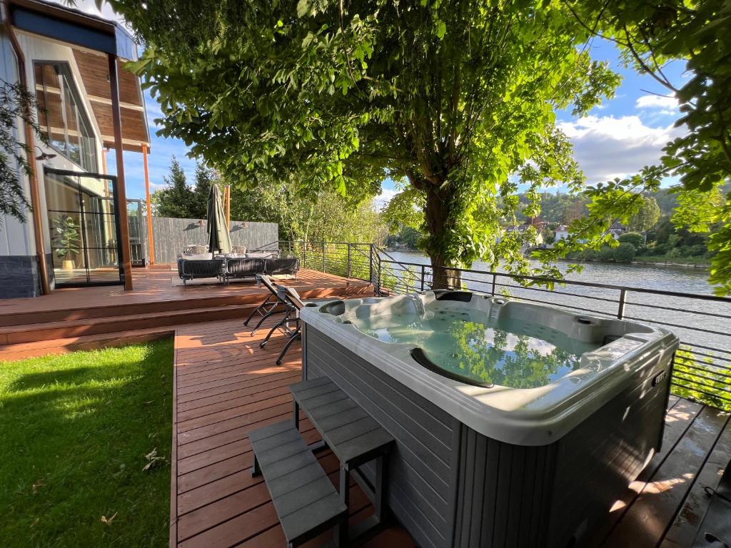 un bain à remous sur une terrasse à côté d'une maison dans l'établissement Chalet sur une île privée avec SPA et SAUNA La Vie Sage, à Villennes-sur-Seine