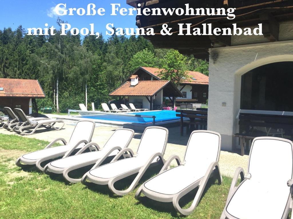 a row of white lounge chairs in front of a swimming pool at Ferienwohnung Ferienanlage Pool Sauna Hallenbad Nähe Skipiste Bayer Wald in Hauzenberg