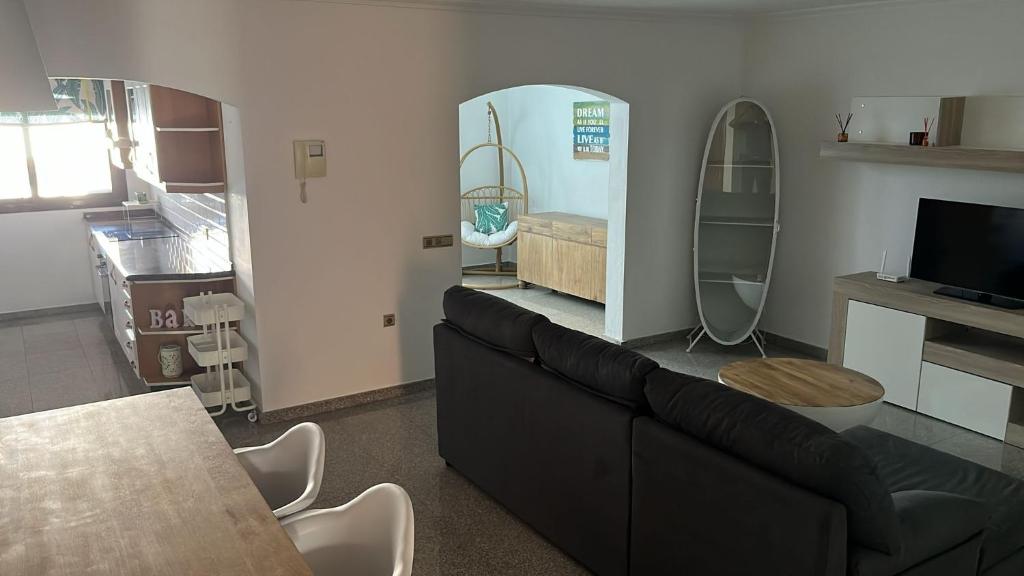 Una sala de estar con un sofá negro y un televisor. en Aquamarina House, en Caleta de Fuste