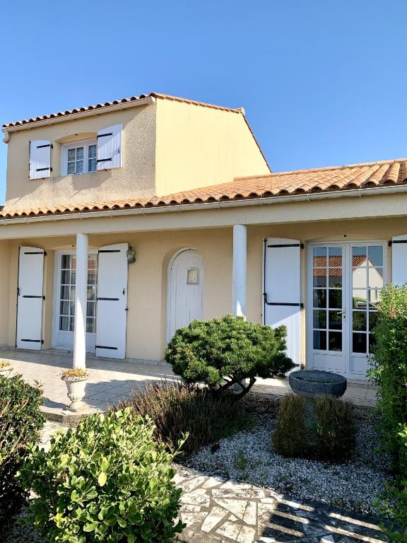 une maison avec des portes, des fenêtres et des buissons blancs dans l'établissement Maison de la Métairie, à Les Sables-dʼOlonne