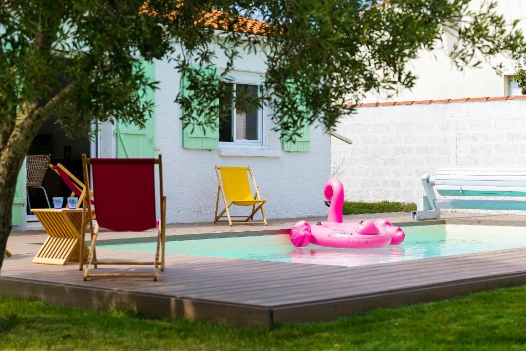 un cygne rose dans une piscine avec des chaises dans l'établissement Superbe maison rénovée avec piscine Les Sables d'Olonne - 8 personnes, à Les Sables-dʼOlonne