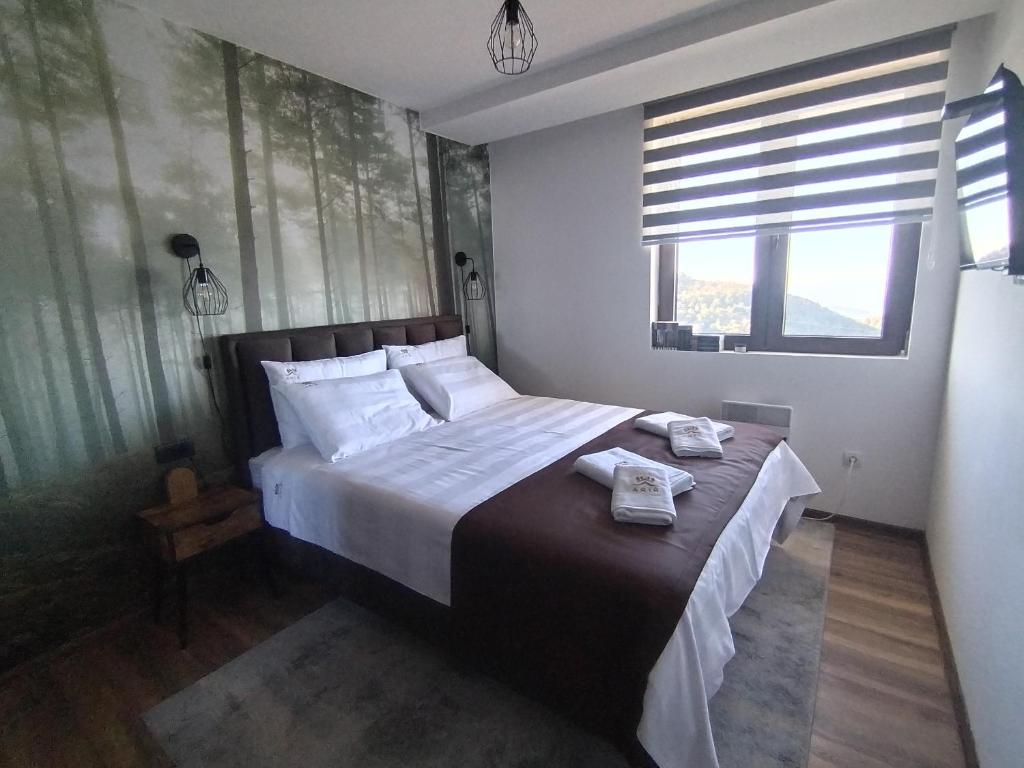 科帕奥尼克Apartman TRAMONTO Kopaonik的一间卧室，有一张大床，床上有两条毛巾