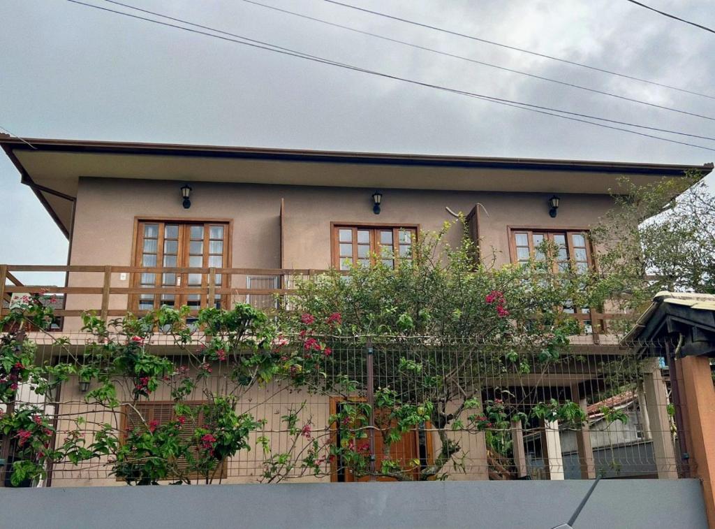 a house with a balcony with flowers on it at Encanto Acomodações in Guarda do Embaú