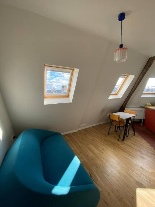 a living room with a blue couch and two windows at Studio Victoria - Centre de Paris in Paris