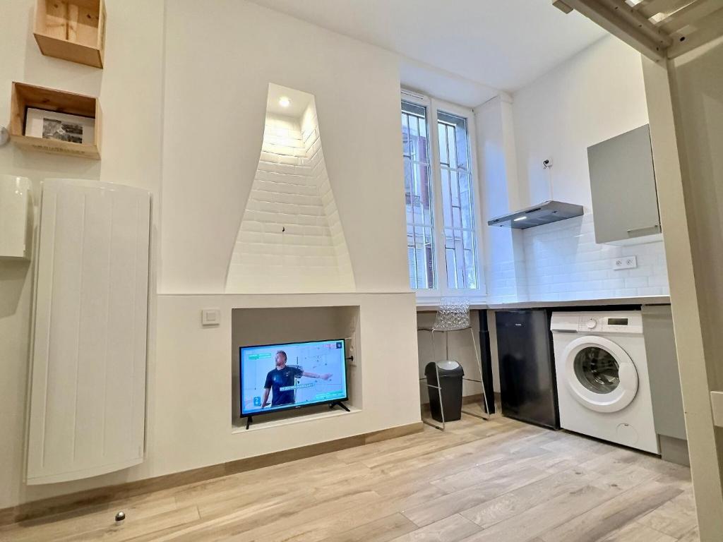 - un salon avec une télévision murale dans l'établissement WonderHost, joli studio rénové vers boulevard des Pyrénées, à Pau