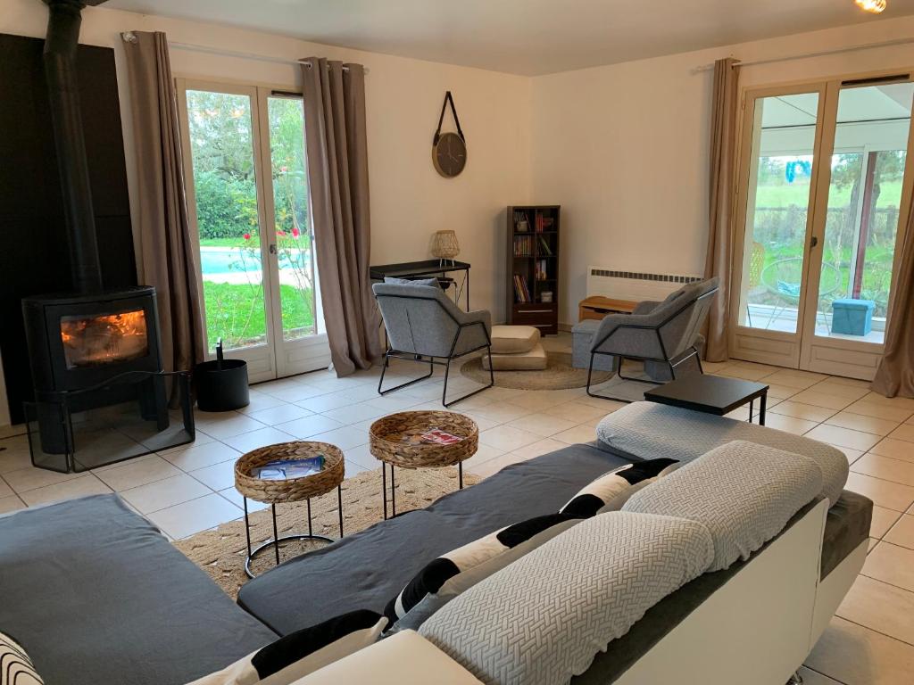 - un salon avec un canapé, des chaises et une cheminée dans l'établissement Gîte 3 étoiles les Gourlines avec balneo, véranda, piscine et garage, à Avermes
