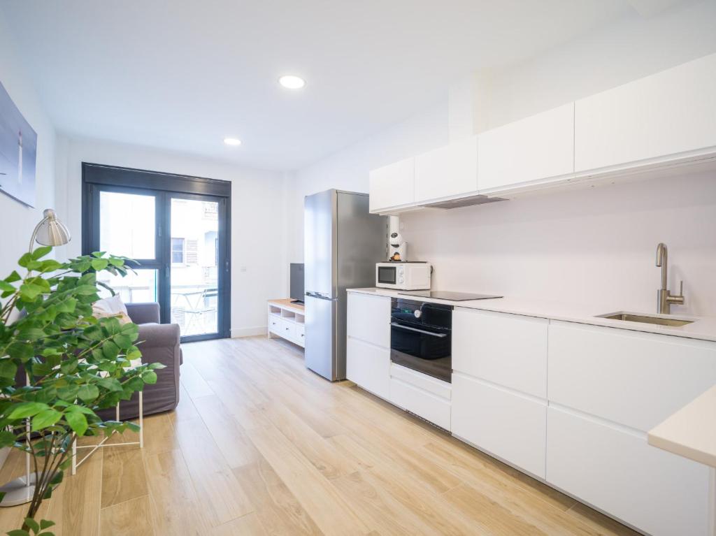 eine Küche mit weißen Schränken und ein Wohnzimmer in der Unterkunft Deluxe Canteras By CanariasGetaway in Guanarteme