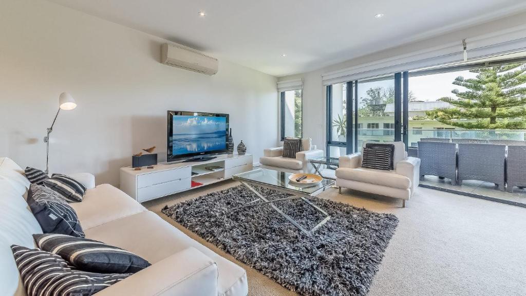 a living room with a white couch and a tv at 9/4 The Esplanade, Cowes - Cscape in Cowes