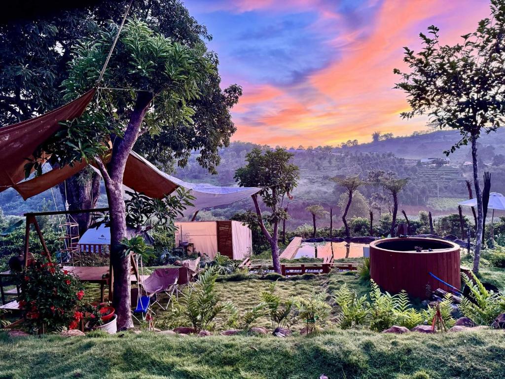 a view of a resort with a sunset in the background at Mầm Farmstay And Camping in Lam Ha