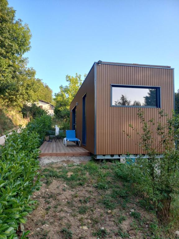 une petite maison en bois avec une chaise bleue sur une terrasse dans l'établissement Tiny house dans l'ouest lyonnais, à Sain-Bel
