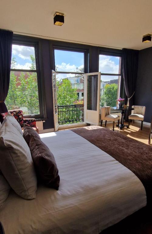 Hotel Canal House The Tannery Amsterdam, a large bed in a bedroom with large windows at Canal House The Tannery Amsterdam in Amsterdam