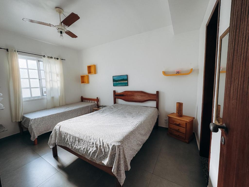 a bedroom with two beds and a ceiling fan at Casa Azul Arraial in Arraial do Cabo