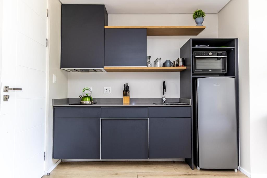 a kitchen with black cabinets and a refrigerator at 4 Lulworth in Johannesburg