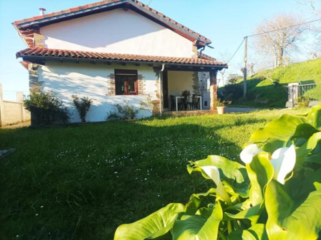 a small white house with a green yard at Casa vacacional Los Enserados in Renedo de Piélagos