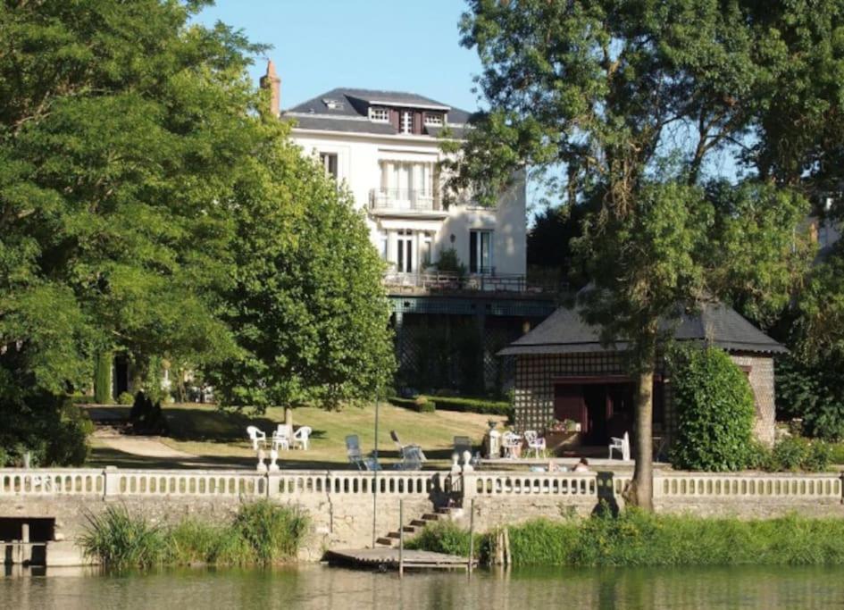 una recinzione bianca di fronte a una casa bianca di Maison de famille de charme en pleine nature en bord de rivière à 20 min d'Angers a Seiches-sur-le-Loir