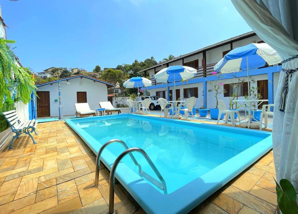 a large pool with chairs and umbrellas on a patio at Pousada Suites Nova Mar Ilhabela in Ilhabela