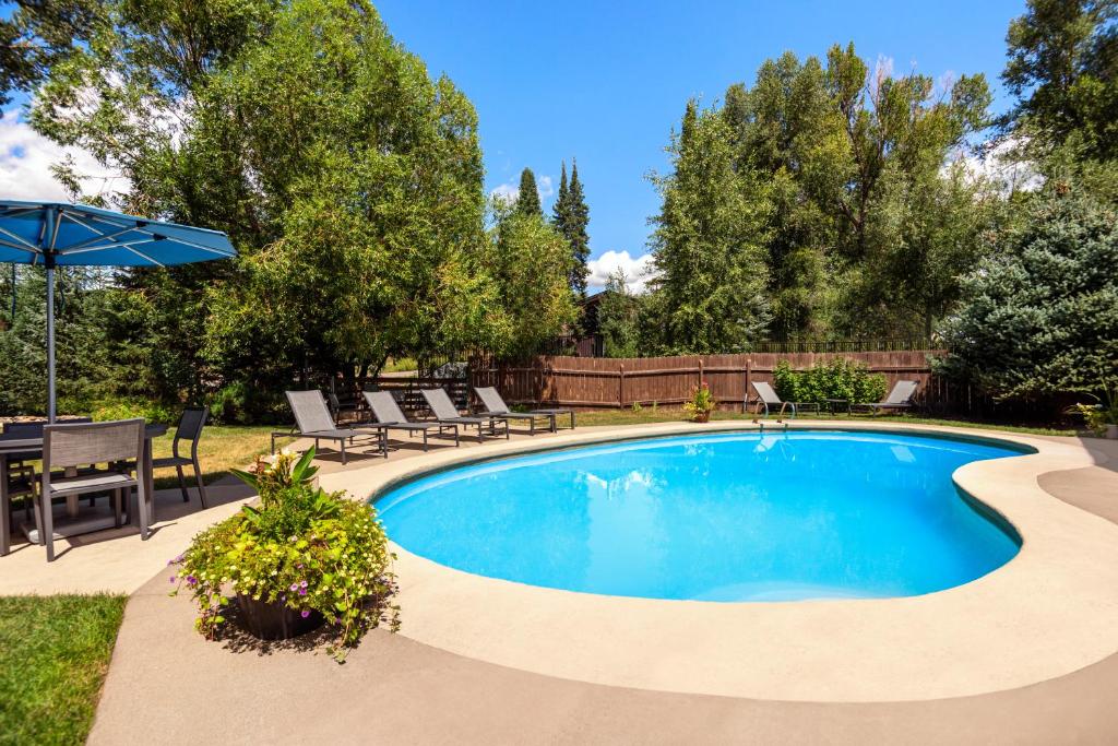 a swimming pool in a yard with chairs and an umbrella at Nordic Lodge in Steamboat Springs