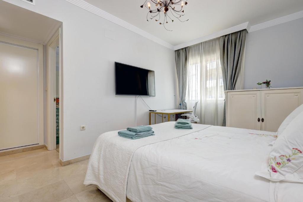 a bedroom with a white bed and a television at Banana Beach primera línea de playa in Marbella