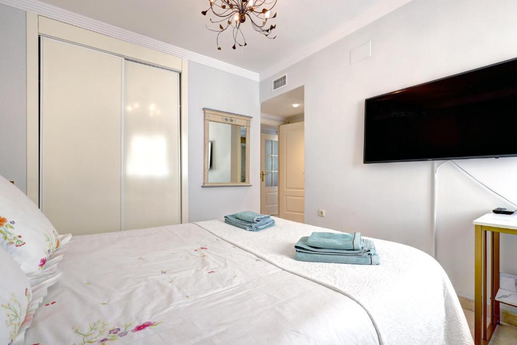 a bedroom with a large white bed with towels on it at Banana Beach primera línea de playa in Marbella