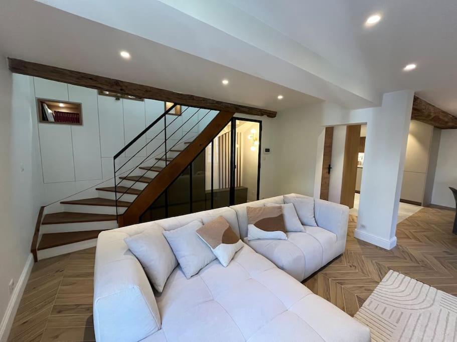 - un canapé blanc dans le salon avec un escalier dans l'établissement Le Triplex du Quai, à Bouchemaine