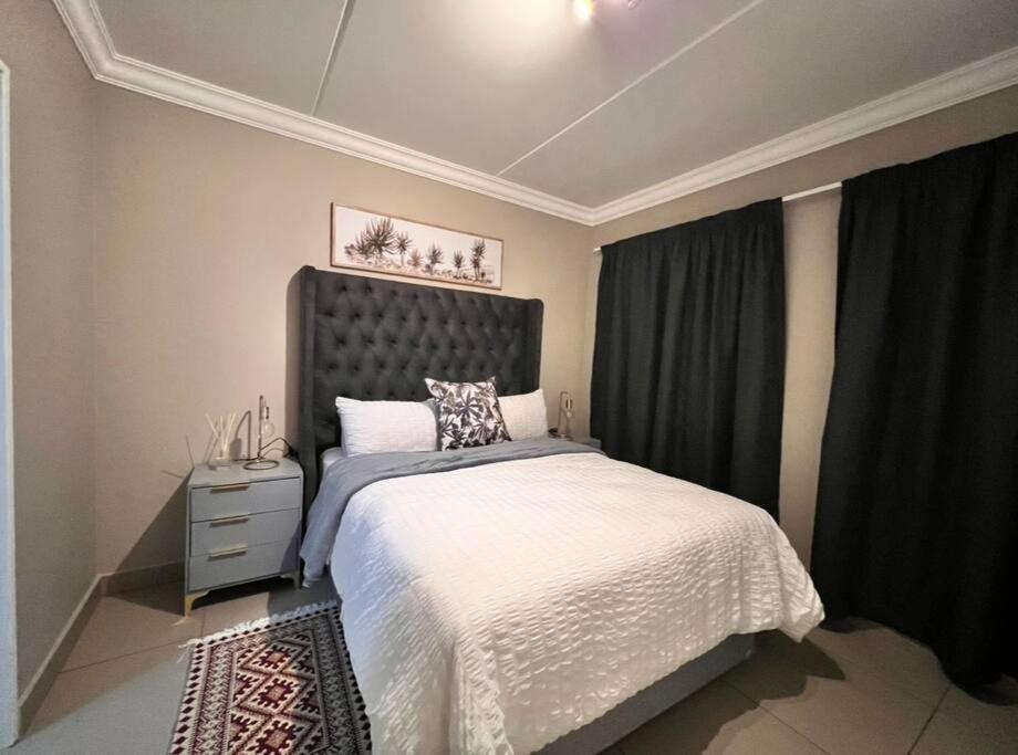a bedroom with a large bed with a black headboard at Experience home away from home! in Chartwell