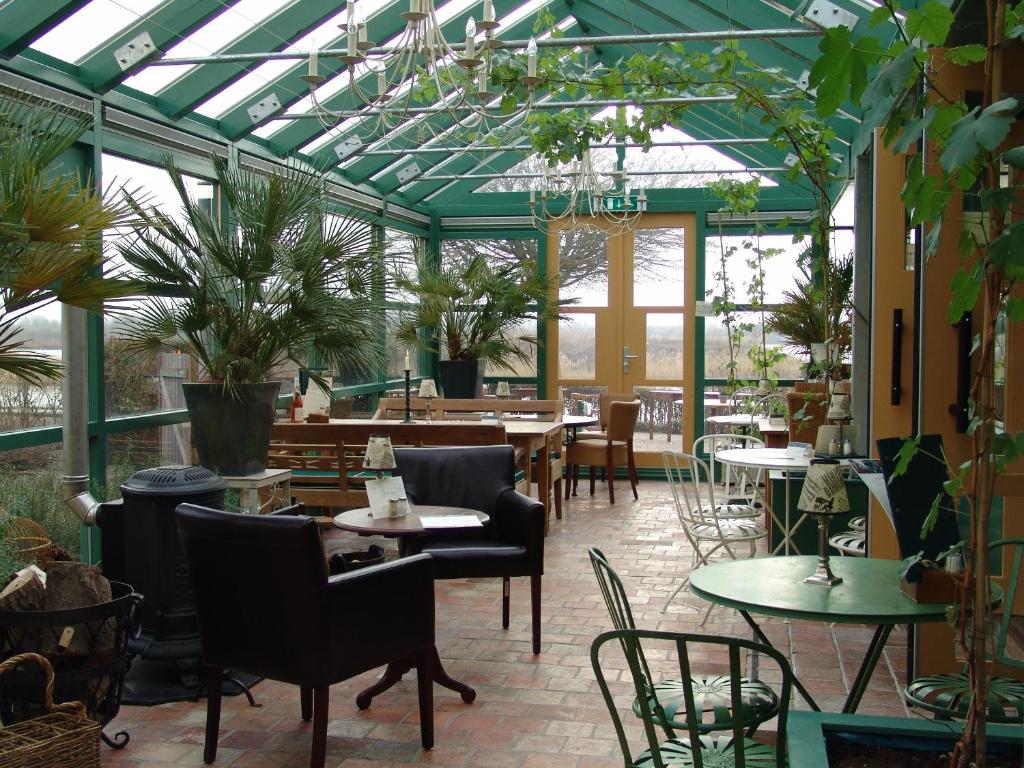 um jardim de Inverno com mesas, cadeiras e plantas em Hajé Hotel Restaurant de Lepelaar em Lelystad