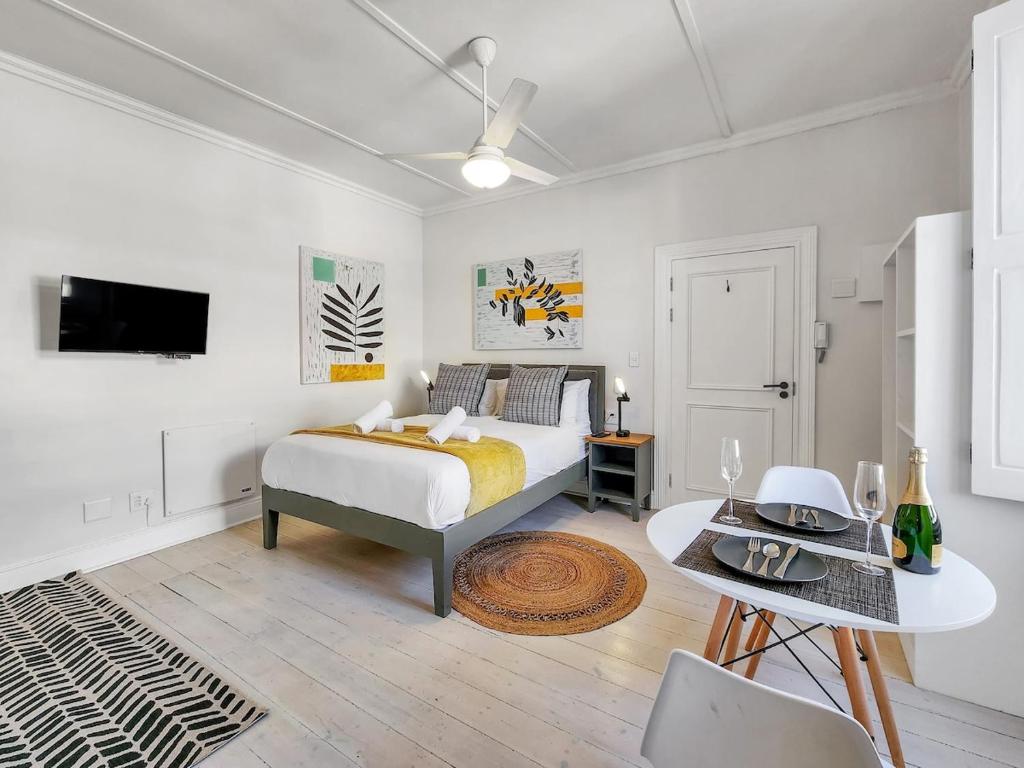 a white bedroom with a bed and a table at Classy and Newly Renovated Studio in Observatory in Cape Town