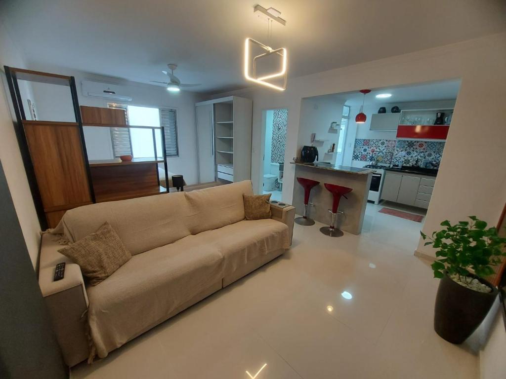 uma sala de estar com um sofá e uma cozinha em Apartamento Estúdio em Caraguatatuba com Garagem em Caraguatatuba