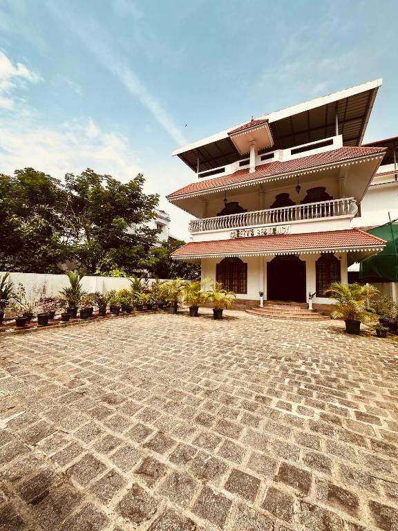 a building with a stone courtyard in front of it at Cleety's Residency in Cochin