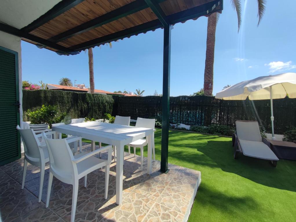 a white table and chairs under a pergola at Bungalow next Yumbo Center in Playa del Ingles