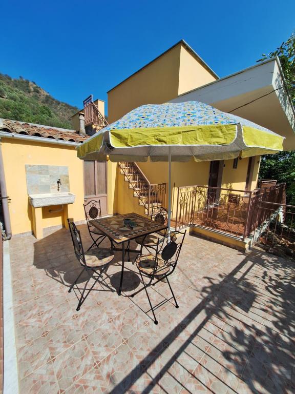 a table and chairs under an umbrella on a patio at Casa Vacanze Geppy e Minù Gole Alcantara in Motta Camastra