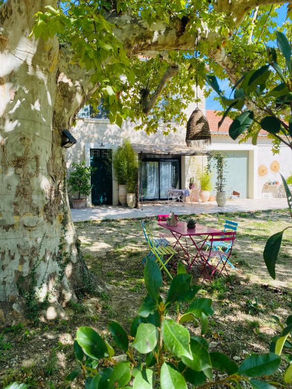 une cour avec une table et des chaises sous un arbre dans l'établissement Gîte Mas La Bohème Piscine Parking Privé L'Isle-Sur-La-Sorgue, à LʼIsle-sur-la-Sorgue
